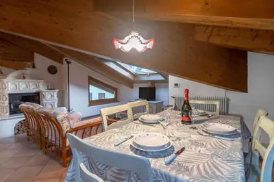 a dining room with a table with a bottle of wine at DolomiApartments - Casa Margherita in Predazzo