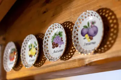 a row of plates on a wooden shelf at DolomiApartments - Casa Margherita in Predazzo