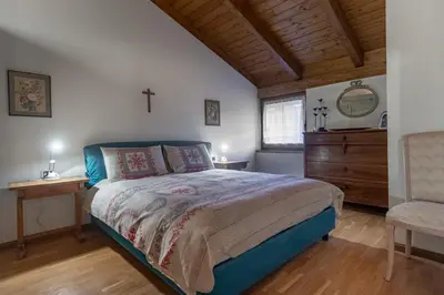 a bedroom with a bed and a cross on the wall at DolomiApartments - Casa Margherita in Predazzo