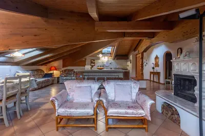 a living room with two chairs and a fireplace at DolomiApartments - Casa Margherita in Predazzo