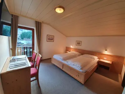 a bedroom with a bed and a desk and a window at Haus Ploner in Castelrotto