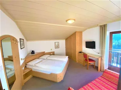 a bedroom with a bed and a desk and a television at Haus Ploner in Castelrotto