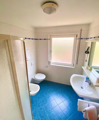 a bathroom with two sinks and a toilet and a window at Haus Ploner in Castelrotto