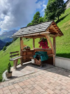 a wooden gazebo with a bench and flowers at Appartamento l’ Aier - Arabba - Dolomiti in Livinallongo del Col di Lana