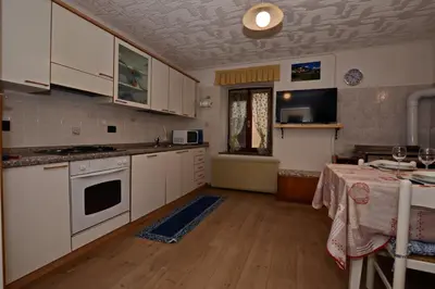 a kitchen with white cabinets and a table in it at App. Valentina in Segonzano
