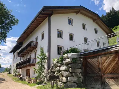 a large white house with a stone wall at Mittersteinerhof in Villabassa