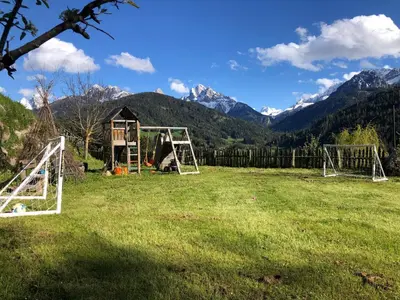 a field with a playground with mountains in the background at Mittersteinerhof in Villabassa