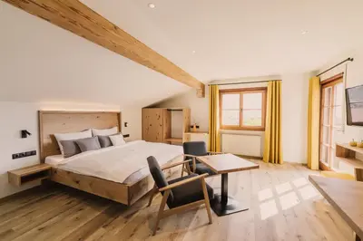 a bedroom with a large bed and a table and chairs at Birkhof in Lana