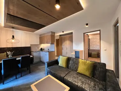 a living room with a couch and a kitchen at Adlhof Apartments in Brunico