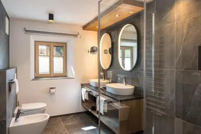 a bathroom with two sinks and two mirrors at Adlhof Apartments in Brunico