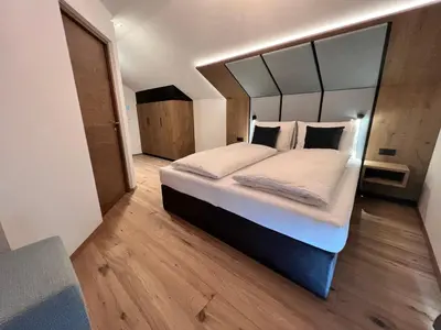 a bedroom with a large bed with a mirror above it at Adlhof Apartments in Brunico