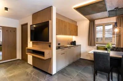 a kitchen with a television and a dining room at Adlhof Apartments in Brunico