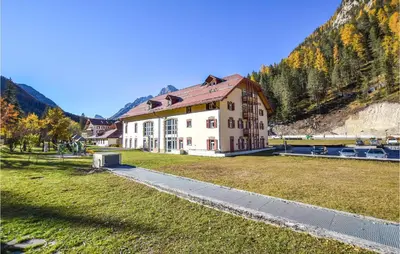 a large building on a grassy field next to a mountain at Amazing Apartment In Località Carbonin in Carbonin
