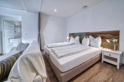 a bedroom with a large bed and a chair at Apartment Römerbrücke - Ponte Romano in Merano