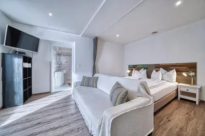 a bedroom with a large bed and a couch at Apartment Römerbrücke - Ponte Romano in Merano