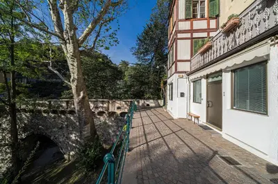 a green bench sitting on a walkway next to a building at Apartment Römerbrücke - Ponte Romano in Merano