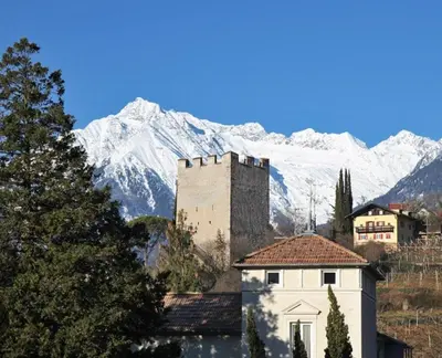 a castle in front of a snow covered mountain at Apartment Römerbrücke - Ponte Romano in Merano