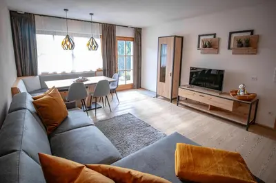 a living room with a couch and a tv and a table at Apartment AEREUS Krumas-Living - Kronplatz in San Lorenzo di Sebato