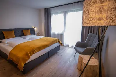 a bedroom with a large bed and a chair at Apartment AEREUS Krumas-Living - Kronplatz in San Lorenzo di Sebato