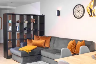 a living room with a gray couch with orange pillows at Apartment AEREUS Krumas-Living - Kronplatz in San Lorenzo di Sebato