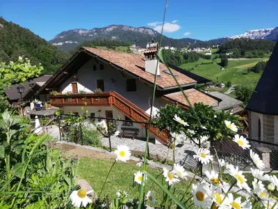 a house on a hill with flowers in the foreground at Gosthof Kastelruth in Castelrotto