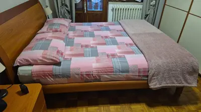 a bed with a pink and grey blanket on it at Appartamento La Casa di Violetta in Tonadico