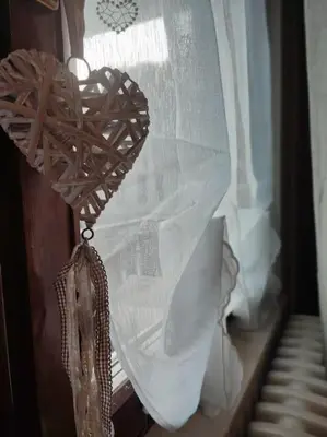 a wooden heart on a window with a curtain at Appartamento La Casa di Violetta in Tonadico
