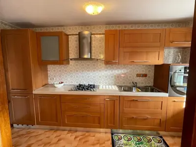a kitchen with wooden cabinets and a stove top oven at Appartamento La Casa di Violetta in Tonadico
