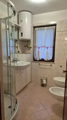 a bathroom with a sink and a toilet and a window at Appartamento La Casa di Violetta in Tonadico