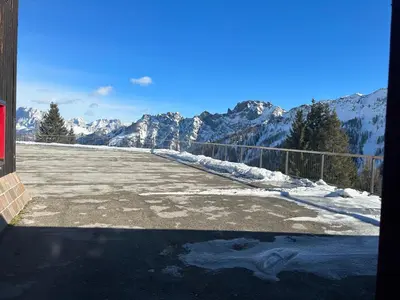 a parking lot with snow covered mountains in the background at Perla Dolomiti Falt in Falcade
