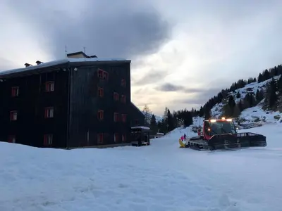 a snow truck parked next to a building in the snow at Perla Dolomiti Falt in Falcade