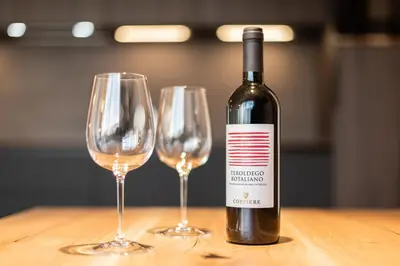 a bottle of wine sitting next to two wine glasses at Small Luxury Apartments Lausa in Valdaora