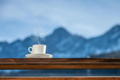 a coffee cup sitting on a table with mountains in the background at Small Luxury Apartments Lausa in Valdaora