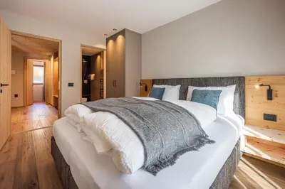 a bedroom with a large white bed and wooden floors at Small Luxury Apartments Lausa in Valdaora