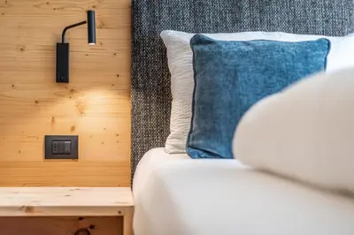 a bed with a blue pillow next to a wooden wall at Small Luxury Apartments Lausa in Valdaora