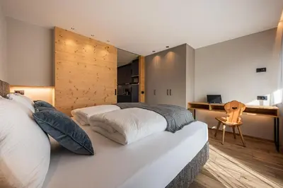 a bedroom with a large white bed and a desk at Small Luxury Apartments Lausa in Valdaora