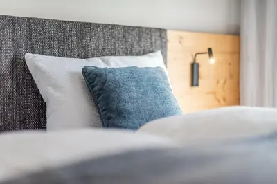a bed with a blue pillow on top of it at Small Luxury Apartments Lausa in Valdaora