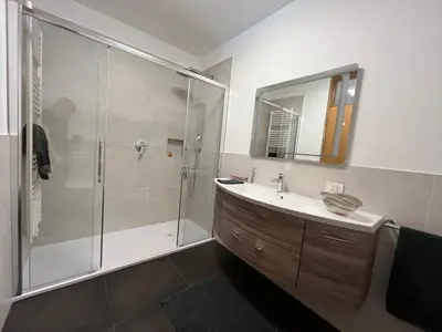 a bathroom with a shower and a sink and a mirror at Luxus Penthouse mit Terrasse, Garage, Fahrradraum und Infrarotsauna in Merano