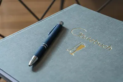 a blue pen sitting on top of a notebook at Luxus Penthouse mit Terrasse, Garage, Fahrradraum und Infrarotsauna in Merano