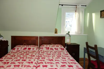 a bedroom with a bed with a red bedspread and a window at Villa Molteni, Ville di Fiemme, Varena in Varena