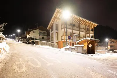 a building on a snow covered street at night at Cesa Antermoia in Mazzin