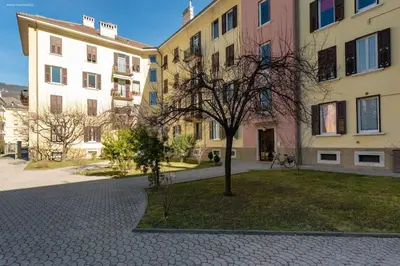 a tree in the middle of a courtyard with buildings at Victoria Apartment in Bolzano