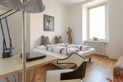 a living room with a couch and a desk with a laptop at Victoria Apartment in Bolzano