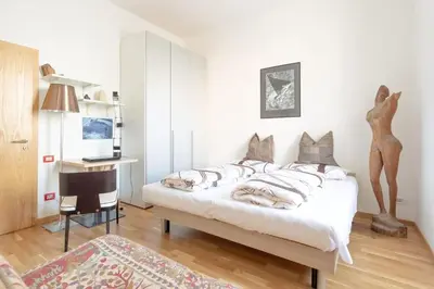 a bedroom with a bed and a desk and a chair at Victoria Apartment in Bolzano