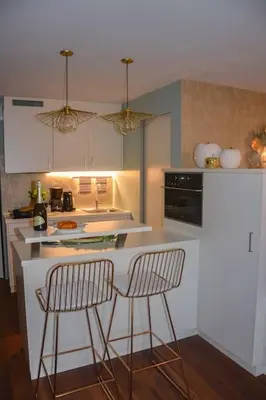 a kitchen with two chairs at a white counter at moderne Ferienwohnung in Merano