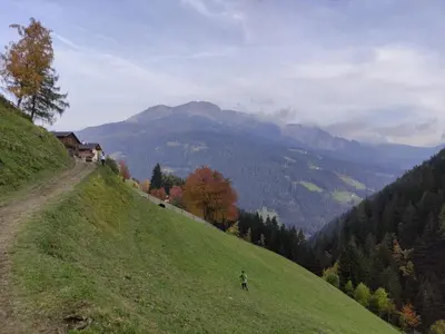 a person walking on a grassy hill with a mountain at Unterweg Hof in Sarntal