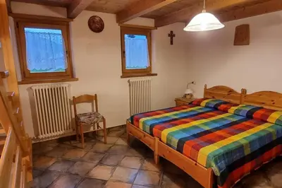 a bedroom with a bed and a chair and windows at Maso Brunetto in Canale San Bovo