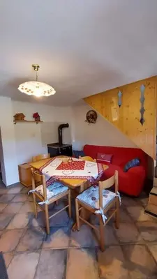 a living room with a table and a red couch at Maso Brunetto in Canale San Bovo