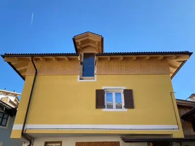 a yellow building with a window and a roof at CASA PARE' B&B in Tesero