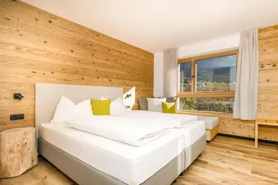 a bedroom with a white bed and a wooden wall at Neuhuberhof in Vols am Schlern